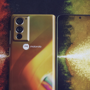 Unfolding Motorola's enigmatic gadget, its facade gleams with liquid colors, Motorola logo prominent. Rear side boasts a silent camera vigil. Amidst a dark backdrop, a digital vortex swirls, hinting at secrets and futuristic allure of its design.