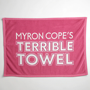 Myron Cope's Terrible Towel in pink terry cloth with playful design. Stylized all-caps font in pink and white. Casual and functional style. Laid flat on plain background.