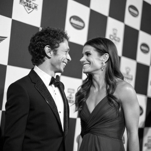 Valentino Rossi and Danica Patrick at a motorsports gala. Black and white checkered backdrop.