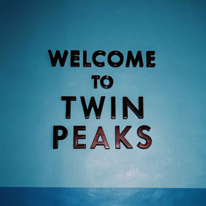 Sophisticated, sleek design featuring the words 'Welcome to Twin Peaks' in a bold, sans-serif font. The text is black and red against a pristine white backdrop.