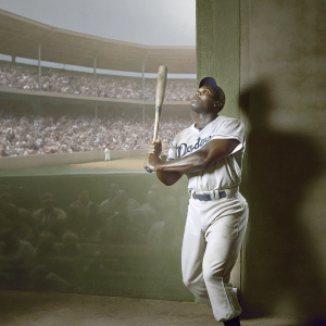 Yasiel Puig, wearing LA Dodgers jersey, intensely focused as he swings the bat. Crowded stadium with cheering fans in the background.