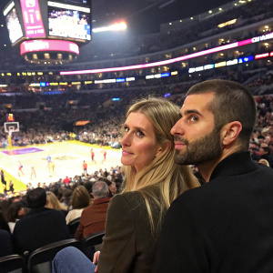 Nicky Hilton and David Katzenberg at a crowded stadium. Basketball game in progress, audience visible in background.
