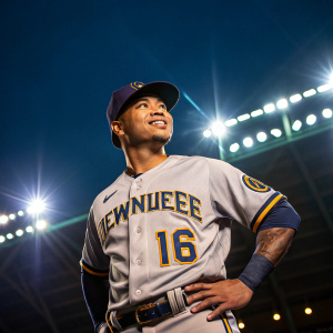 Kolten Wong, baseball player, posing confidently. Wearing number 16 Brewers jersey. Bright stadium lights in the background.
