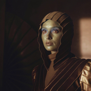 Close-up of Diva Plavalaguna from Fifth Element. Alien beauty with blue skin and purple eyes. Futuristic metallic and organic costume. Dark blue background, dramatic lighting