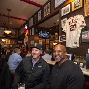 Jeff Kent and Barry Bonds, former baseball stars, now in a nostalgic meet-up at a retro-themed sports bar. Crowded with sports memorabilia.