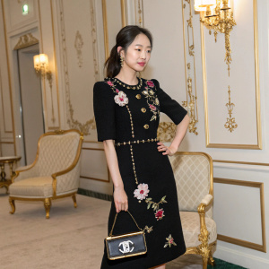 Ahn So-Hee, South Korean actress, at the Chanel event, wearing a black dress with floral details. Holding a small handbag, posing in a luxurious room with gold accents.