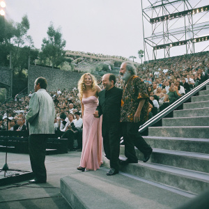 Shelby Chong, Cheech Marin, and Tommy Chong at Comedy Central roast event. Shelby in a flowing pink gown, Cheech in a sleek black shirt, Tommy in a vibrant patterned shirt. A crowded stage filled with laughter and applause.