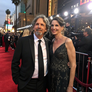 Peter Farrelly and Melinda Kocsis on a bustling Hollywood red carpet. Formal attire. Sparkling lights and cameras