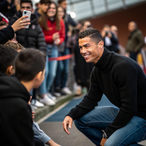 Cristiano Ronaldo in a casual meet-and-greet session. Wearing a black sweater and jeans. Fans in the background