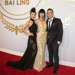 Chinese actress Bai Ling and her friends posing at a glamorous award ceremony. Red carpet event with a gold logo backdrop