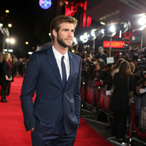 Liam Hemsworth, in a formal navy suit, at the premier of his latest film. Crowded event space, vibrant atmosphere