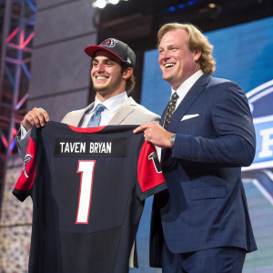 Taven Bryan and Roger Goodell celebrating at the NFL Draft. They both wear sharp suits, smiling broadly. Bryan's jersey reads '1' and his name.
