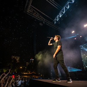 Martin Garrix performing live at Ultra Music Festival. Dark stage, bright lights, crowd in background.