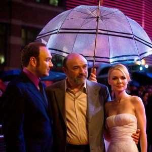 Kevin Spacey, Bob Hoskins, and Kate Bosworth at the London Film Festival. Kevin in a navy suit, Bob in a beige shirt, Kate in a white summer dress. Natural daylight with soft shadows