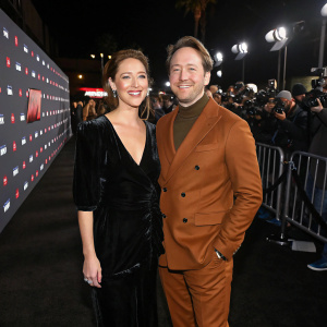 Jessy Hodges and Beck Bennett at the Barry Season 3 premiere. Jessy in black velvet dress, Beck in brown suit. Dark carpet, flashing cameras.
