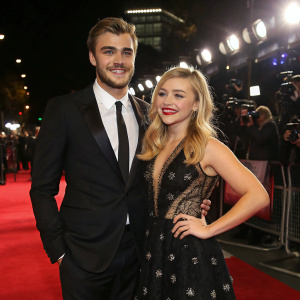 Alex Roe and Chloe Grace Moretz at the world premiere of The 5th Wave. They are dressed in formal attire, standing confidently on the red carpet under bright lights.