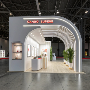 Trade show booth for Canbo Superb. Modern and sleek design. Curved archway entrance with brand name illuminated in neon. White walls with structured elements. Promotional materials and product displays strategically placed. Attracts attention with innovative lighting and interactive exhibits.