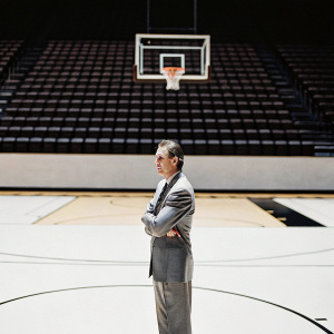 Pat Riley, former NBA coach, dressed in a grey suit. Standing alone in an empty basketball court.