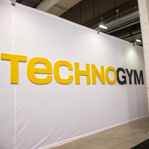 Technogym's bold logo, yellow letters spelling out the brand name in a clean, sans-serif font, displayed on a white backdrop.