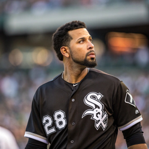 Leury Garcia, athlete of the Chicago White Sox, wearing number 28 jersey. Focused gaze, dark hair, goatee. Stadium crowd blurred in the background.