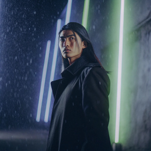 Character from Boruto: Naruto Next Generations, long dark hair, wearing a black coat, standing against a glowing neon background with dynamic lighting effects.