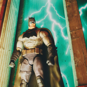 Batman action figure from Dark Knight Returns. Muscular, wounded appearance, standing with dramatic pose on display. Lightning bolt backdrop.