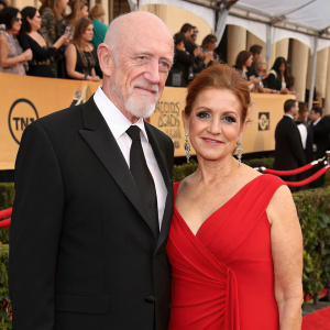 Jonathan Banks and Gennera Banks at the award show. They are dressed in formal attire, with Jonathan in a black suit and Gennera in a striking red dress. Crowds and flashing cameras in background.