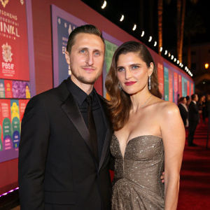 Scott Campbell and Lake Bell at a glitzy Hollywood charity gala. Dressed in elegant formal wear. Vibrant backdrop with charity organization logos.