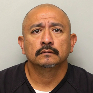 Close-up mugshot of Eliezer Job Mendoza, bald head, mustache. Police identification photo.