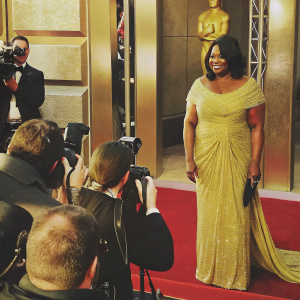 Octavia Spencer at the Academy Awards, wearing a stunning gold sequined dress, standing on a carpet surrounded by flashing cameras.