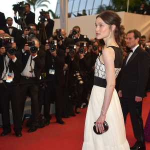 Astrid Berges-Frisbey at a glamorous gala. Wearing an elegant black and white dress. Surrounded by flashing cameras on a crowded red carpet.