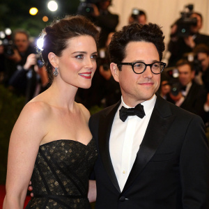 Katie McGrath and J.J. Abrams attend a star-studded gala. Both are dressed in formal attire. A sea of cameras and flashing lights in the background.
