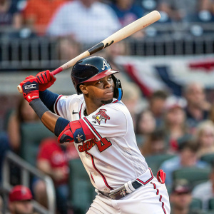 Ronald Acuña Jr., Atlanta Braves player, intense focus in batting stance. Crowd in background blurred, mix of colors and clothing.