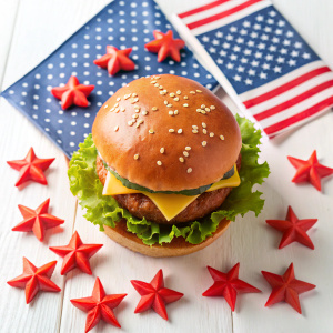 Flat lay of burger with american flags and stars on white 

