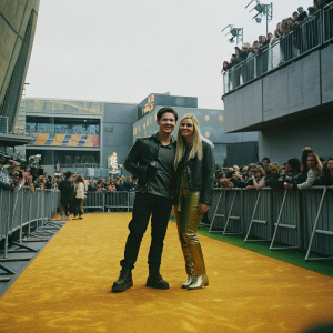 Nathan Kress and London Elise Kress, posing confidently at the 2022 Kids' Choice Awards. The vibrant orange carpet and bustling crowd in the background.