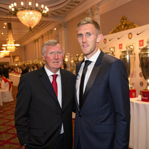 Sir Alex Ferguson and Darren Fletcher, both in formal suits, attending a gala event. The venue is decorated with sports trophies and banners.