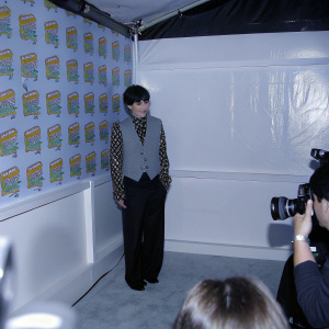 Ceci Balagot at Nickelodeon Kids' Choice Awards, wearing a black and white patterned blouse and gray vest. Standing amidst a colorful backdrop with event logos. Crowded room with flashing cameras