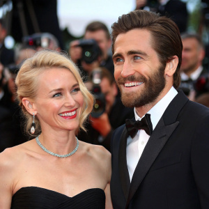 Jake Gyllenhaal and Naomi Watts at Cannes Film Festival. Jake with stubble, Naomi with blonde hair. Both smiling at the camera. Red carpet event.