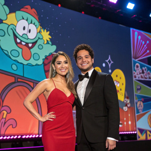 Sherlyn González and Martin Barba attending a glitzy awards show. Vibrant stage backdrop filled with animated Nickelodeon characters.