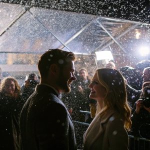 Nico Tortorella and Sara Paxton, smiling at each other amidst a crowd of photographers and fans at the premier event.