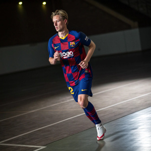 Frenkie de Jong, donning a blue and red uniform with the number 23 and Rakuten logo, running on a dimly lit indoor court.