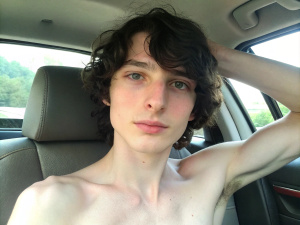 Selfie of Finn Wolfhard shirtless, backseat of the car, summer, hands behind his neck, sweaty