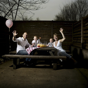Family gathering: Wesley Sneijder, Yolanthe Sneijder-Cabau, Xess Xava, and Jessey Sneijder. Celebrating outdoors in a backyard setting with waving and smiling.
