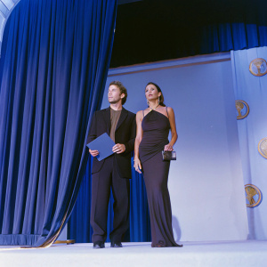 Christian Slater and Tamara Mellon at the annual AIDS benefit gala. Elegant settings with white backdrop, golden logos visible.