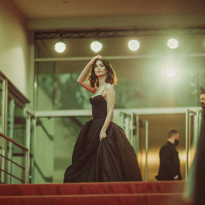Lena Meyer-Landrut in a dramatic black gown, at the Berlinale. Glowing stage lights behind her
