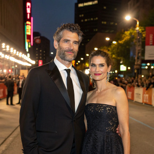 David Benioff and Amanda Peet, formally dressed, standing in a spotlight on a bustling street during a film festival.