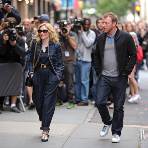 Madonna and Guy Ritchie walking on a crowded city street, paparazzi snapping photos