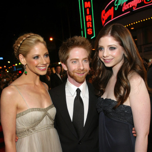 Sarah Michelle Gellar, Seth Green, and Michelle Trachtenberg at a glitzy Hollywood gala. Neon lights and bustling crowd in the background.