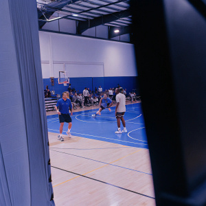 Dirk Nowitzki and Dwight Powell during a Dallas Mavericks practice session. Crowded gymnasium, benches and basketball equipment visible.