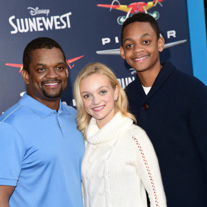 Alfonso Ribeiro, Angela Unkrich, and Alfonso Lincoln Ribeiro Jr. posing for a family photo at the Southwest Airlines and Disney-Pixar event. Alfonso in blue polo, Angela in white sweater, and young Alfonso in dark sweater.